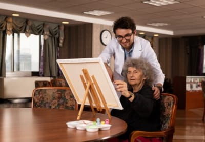 New York Center for Rehabilitation & Nursing, Nursing Home in Astoria, NY — Art therapy session with an elderly woman and caregiver