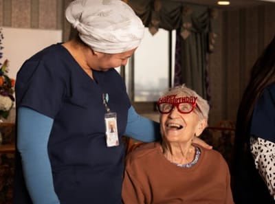 New York Center for Rehabilitation & Nursing, Nursing Home in Astoria, NY — Caregiver celebrating a resident's birthday with festive glasses