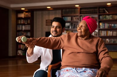 New York Center for Rehabilitation & Nursing, Nursing Home in Astoria, NY — Therapist assisting senior with exercise in communal setting