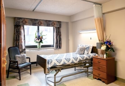 Cozy resident room with bed, chair, and flowers