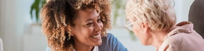 A caregiver smiling with a resident in a bright room