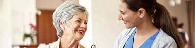A caregiver smiling with an elderly resident indoors
