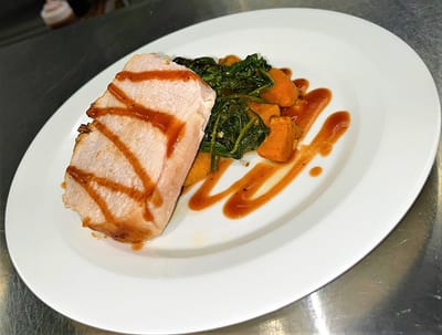 A plate of sliced pork with vegetables and sauce