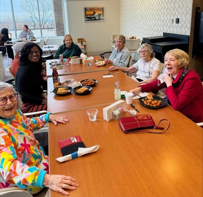 Residents enjoying a meal and conversation in a dining room