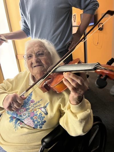 Senior resident playing violin in a bright interior