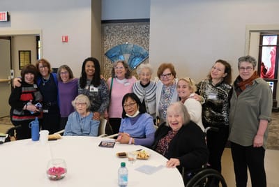 Residents and staff gathered around a table smiling
