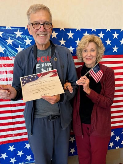 Residents celebrating with flags and a certificate