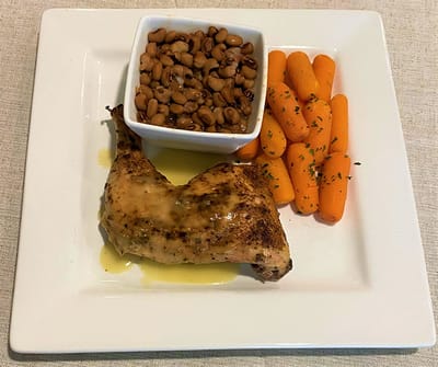 A plated meal of chicken, beans, and carrots