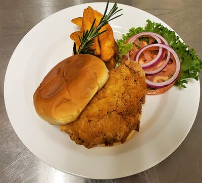 A plate with fried chicken sandwich and sides