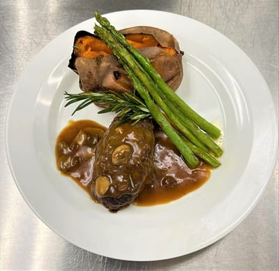 Plate of food featuring steak, sweet potato, and asparagus