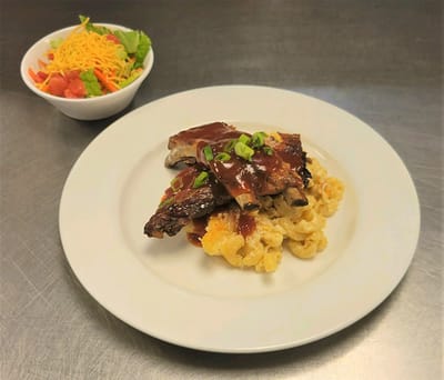 A plate of barbecue with macaroni and salad