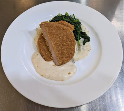 Plate of breaded chicken with vegetables and sauce