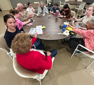 Residents and volunteers engaged in an art activity at a table