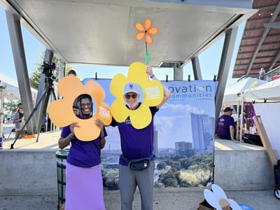 Two people holding flower-shaped signs at an outdoor event