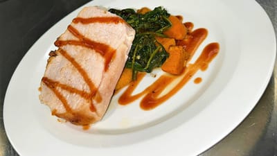 Plate of pork with vegetables on a white dish