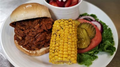 Pulled pork sandwich with corn and salad