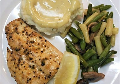 A plate of baked fish with vegetables and mashed potatoes