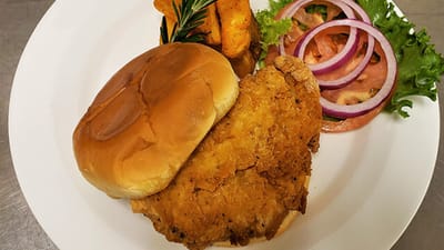 A plate with fried chicken sandwich and sides
