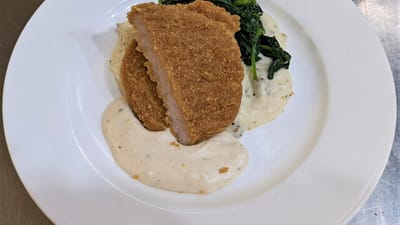 Plated chicken dish with sauce and greens