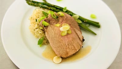 A plated meal with pork, rice, and asparagus
