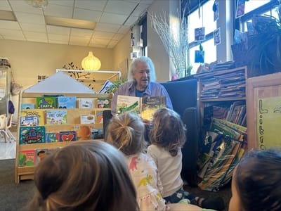 A resident reads a book to children in a warm setting