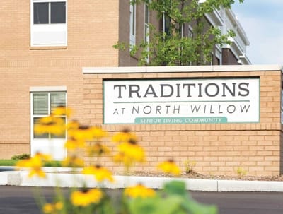 Exterior sign of Traditions at North Willow with flowers