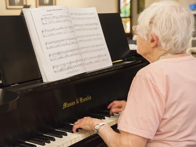 Older adult playing piano in a bright room