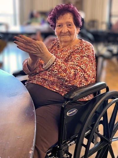 Senior resident in a wheelchair smiling at a common area