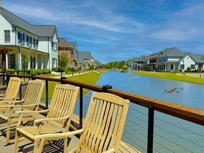 Outdoor seating area with a pond and houses in the background