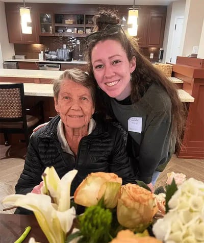Resident and staff member smiling together at a table