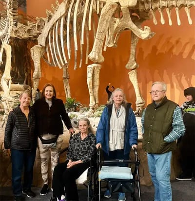 Residents posing in front of a large dinosaur skeleton