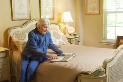 A senior woman reading a book in her room.