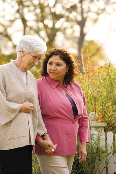 Two women walking together in a garden.