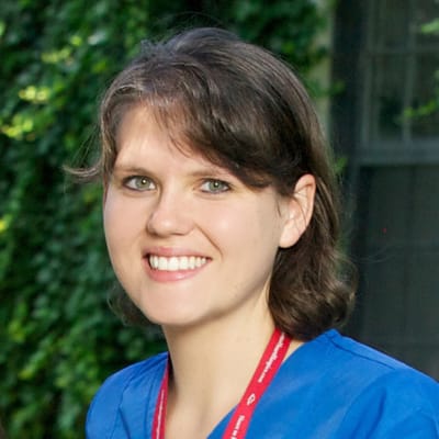 Nurse smiling in outdoor area with greenery