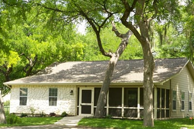 Single-story building surrounded by trees.