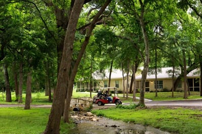 Residents riding in a golf cart on the facility grounds.