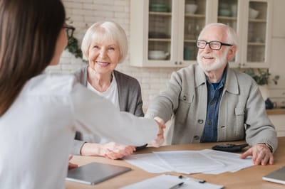 Two seniors happily interacting with a staff member.