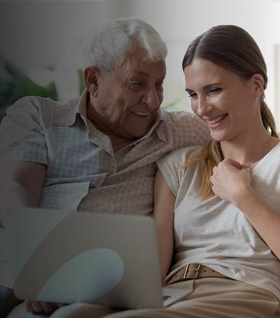 A resident enjoying time with a caregiver on a laptop.