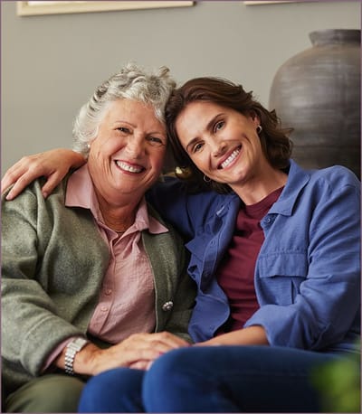 Senior resident and staff member smiling together.