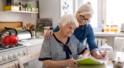 A caregiver assisting a senior in a kitchen