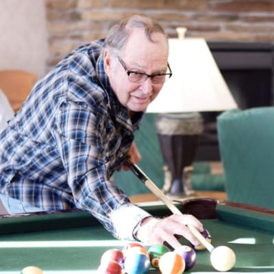 Resident enjoying a game of billiards indoors.