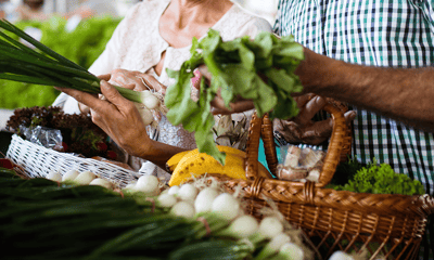 Hands selecting fresh vegetables at a market