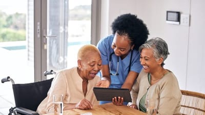 Residents engaging with staff and a tablet.
