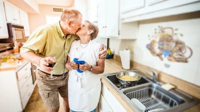 A couple cooking together in a kitchen.