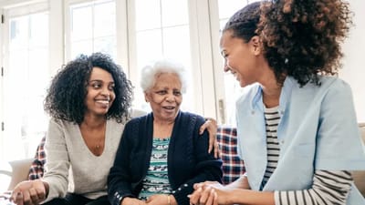 Smiling women engaging with an elder in a bright room.