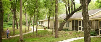 Resident walking a dog along a pathway in the facility grounds.