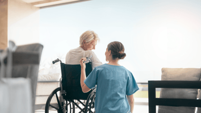 Care staff assisting a resident in a wheelchair.