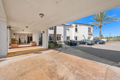 Exterior view of a senior living facility entrance with palm trees