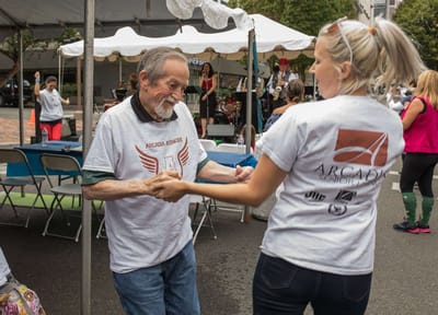 Senior resident dancing with staff at an outdoor event