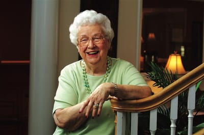 Smiling elderly woman seated by a staircase